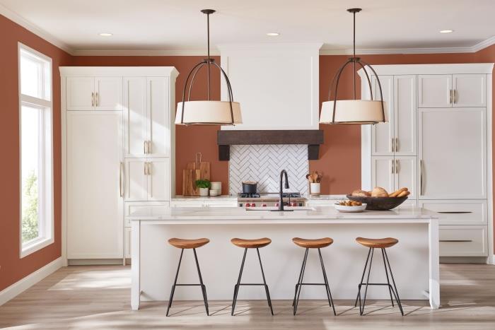 baltos virtuvės dizaino centro salos išdėstymas terakotos spalvos dažai mediena ir metalinė baro kėdė balti virtuvės baldai