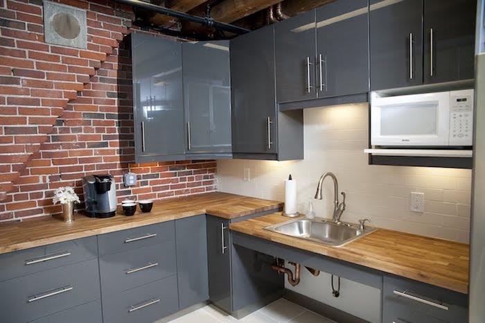 moderni pilka lakuota virtuvė, interjeras su plytų siena, pramoninė virtuvės dekoracija