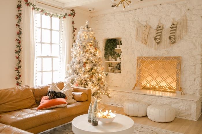 Ahşap zemin ve deve derisi mobilyalar ile beyaz bir oturma odasında koza atmosferi, beyaz ve gri Noel ağacı ile orijinal Noel dekoru