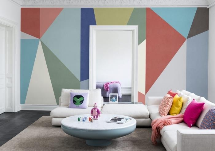 notranje oblikovanje trend geometrijsko slikarstvo dnevna soba stenski naglas beli kotni kavč okrasne blazine okrogla mizica