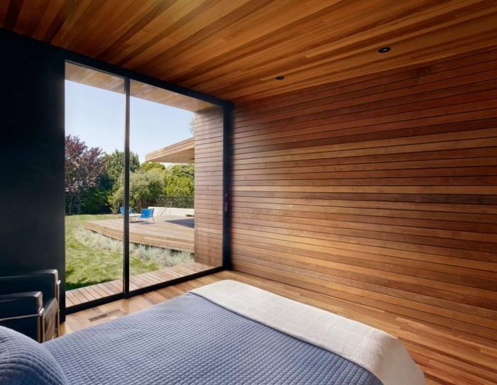 minimalistinis miegamasis su lubomis ir rudomis medinėmis grindimis, idėja uždengti miegamojo sienas medinėmis plokštėmis