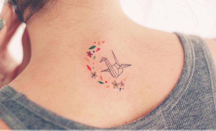 majhna minimalistična tetovaža na zadnji strani vratu, ki združuje cvetlične motive in origami žerjava