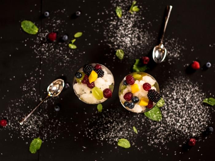 lengvas desertas kreminis sūris šviežių vaisių desertas dubenyje stiklinė gervuogės avietės mango griežinėliai šaukštas desertas mėtų lapai