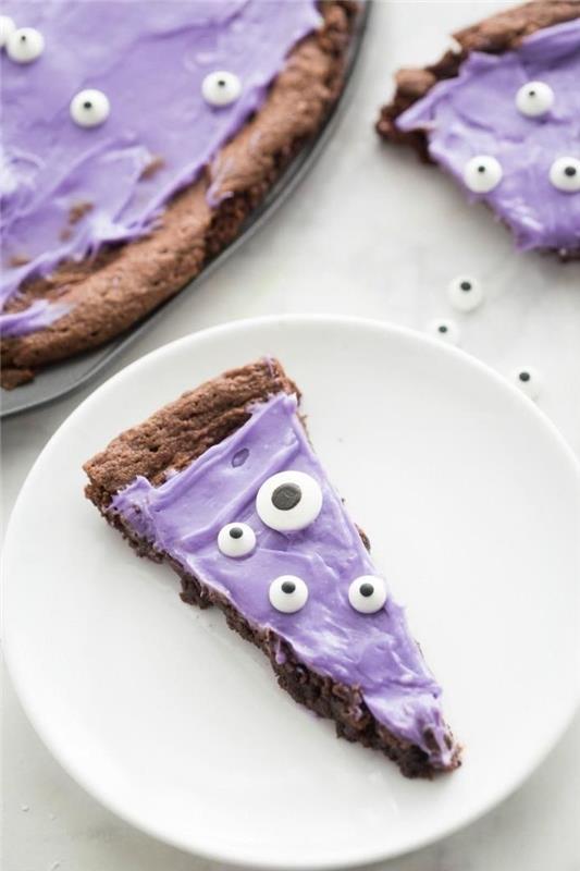 Halloween monster brownie pizza z vijolično masleno kremo, okrašena s sladkarijami za oči, izvirna tematska sladica za obrok za noč čarovnic