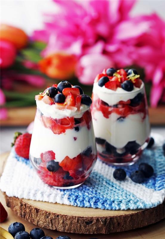 lahka sadna sladica steklena sladica jogurt in sveže sadje jagode borovnice lesena deska pladenj za sladice modri in beli prtički rože tulipani