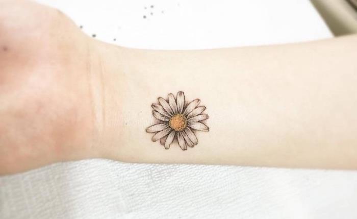srčkan model preproste tetovaže v cvetličnem dizajnu, risba s črnilom z marjetico, tetovirano na zapestju