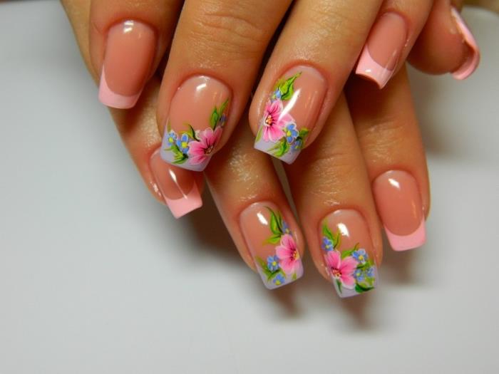 Model za nail art v francoskem slogu s pastelno rožnatim lakom na konicah nohtov in cvetličnim okrasjem v rožnato zeleni in modri izvedbi