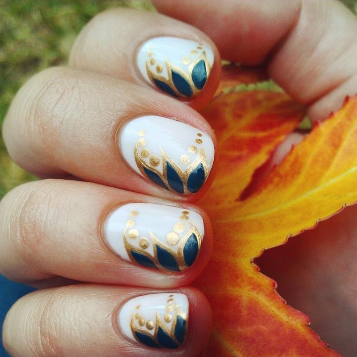 risba na nohte v obliki jesenskega lista v temno modrem laku z obrisi v zlatih lakih pike ukrivljene črte enostavno nail art