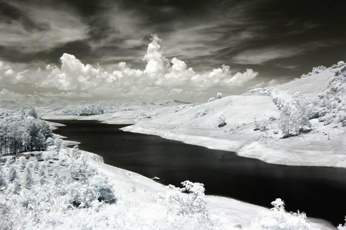 kraštovaizdžio fonas, gražus kraštovaizdis, upė žiemą, balti debesys tamsiai pilko dangaus fone, nespalvota nuotrauka