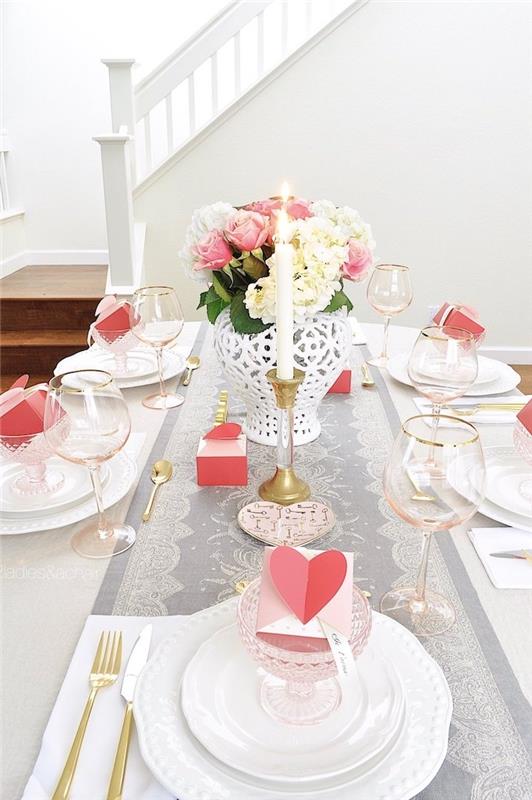 vakarienė prie žvakių šviesos gėlėmis dekoruotas stalas, audinio bėgikas ir mažos kortelės lėkštėse