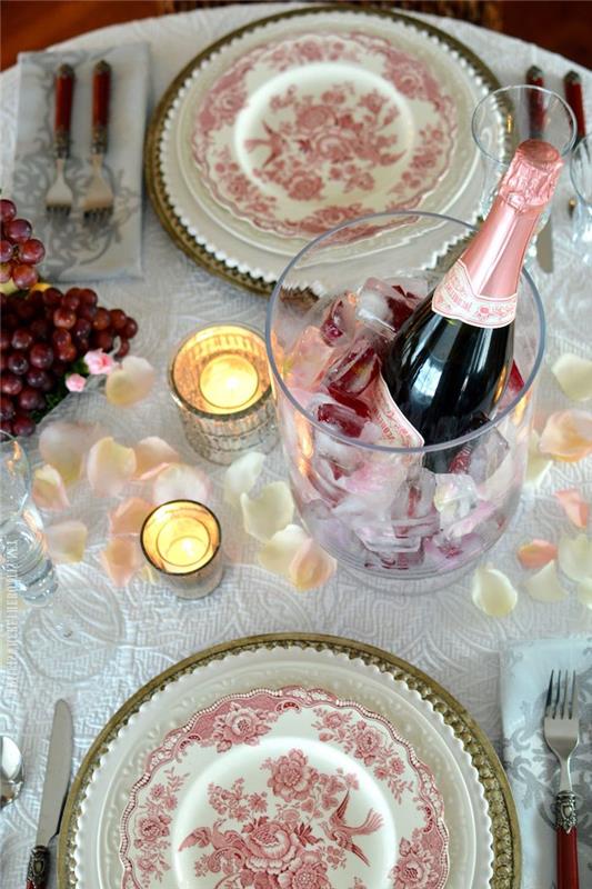 romantična večerja z dvema porcelanskima krožnikoma, vedrom šampanjskih sveč in cvetnimi listi vrtnic