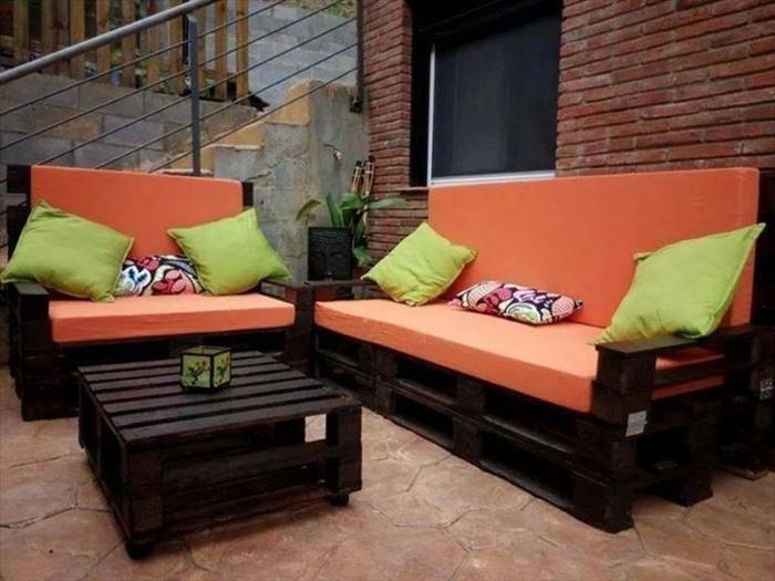 Ideja divano bancali di colore scuro, materassi di colore arancione e cuscini verdi