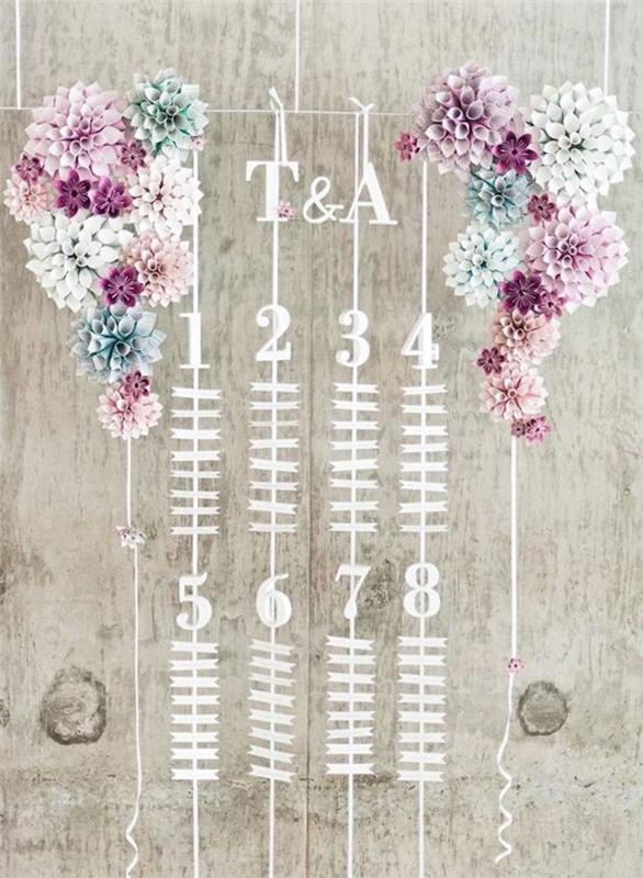 vestuvių stalo planas, mažos etiketės su svečių vardais ir spalvinga popierinė gėlių puošmena iš abiejų pusių
