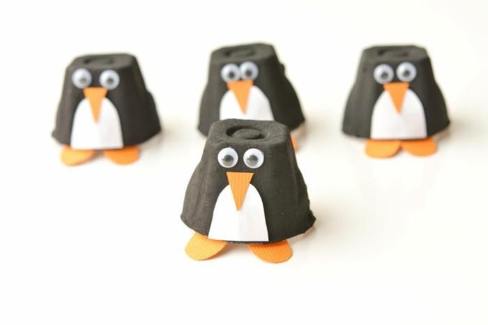 DIY za vašo sobo, štirje okraski za pingvine, izdelani iz črnih kartonskih skodelic, okrašeni z belimi in oranžnimi teksturiranimi papirnatimi detajli in se lepijo na oči