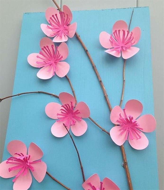 DIY projekti za otroke, majhna vejica, okrašena s cvetovi češenj, izdelana iz papirja v dveh odtenkih roza, na bledo modrem ozadju