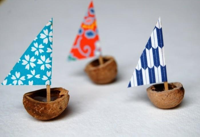 enostavne otroške obrti, trije čolni iz orehovih lupin, okrašeni s pisanimi trikotnimi krep papirnatimi jadri na zobotrebcih