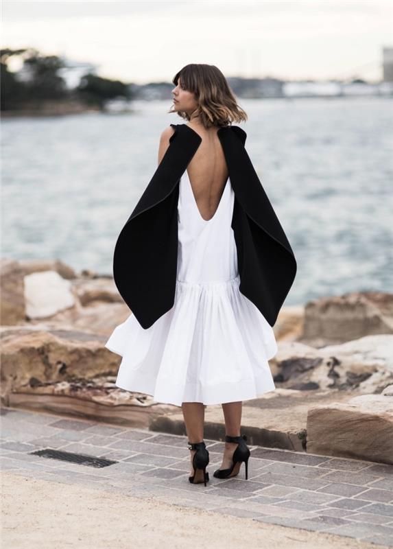 yüksek ayakkabı ile kombinlenmiş sırt dekolteli beyaz ve siyah renkte şık ve trendy gece elbisesi örneği