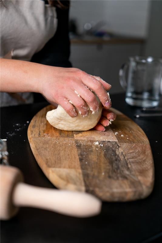 ahşap kesme tahtası üzerinde hamur, naan ekmeği, siyah yüzeye yerleştirilmiş