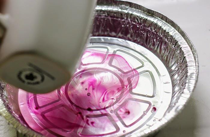 „Dyi“ dovanų idėjos, puodelis šalia alavinio folijos dubenėlio, pripildytas vandens ir atskiesto raudono rožinio nagų lako