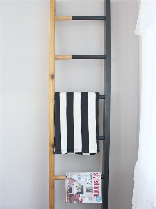 lesena deko lestev, napol prebarvana v črno, skladišče revij in tekstila, osrednja točka v sodobni dnevni sobi