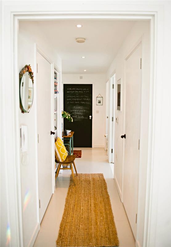bej halı ve arduvaz boya kapı ile beyaz koridor, sarı yastık ve yuvarlak ayna ile dekorasyon