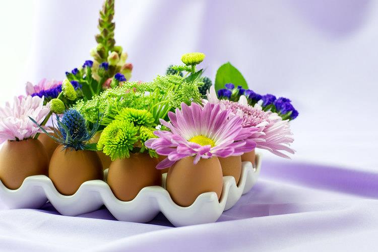 beyaz tutucuya yerleştirilmiş yumurtalar, eğlenceli ve kolay el sanatları, uçuk mor, yeşil ve mavi çiçeklerle süslenmiş