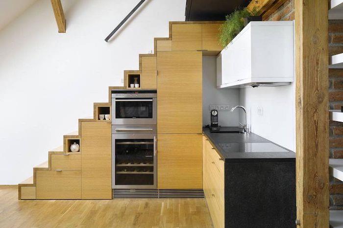 aparati iz nerjavečega jekla in omara pod lesenimi stopnicami kuhinjski les in minimalistična črna