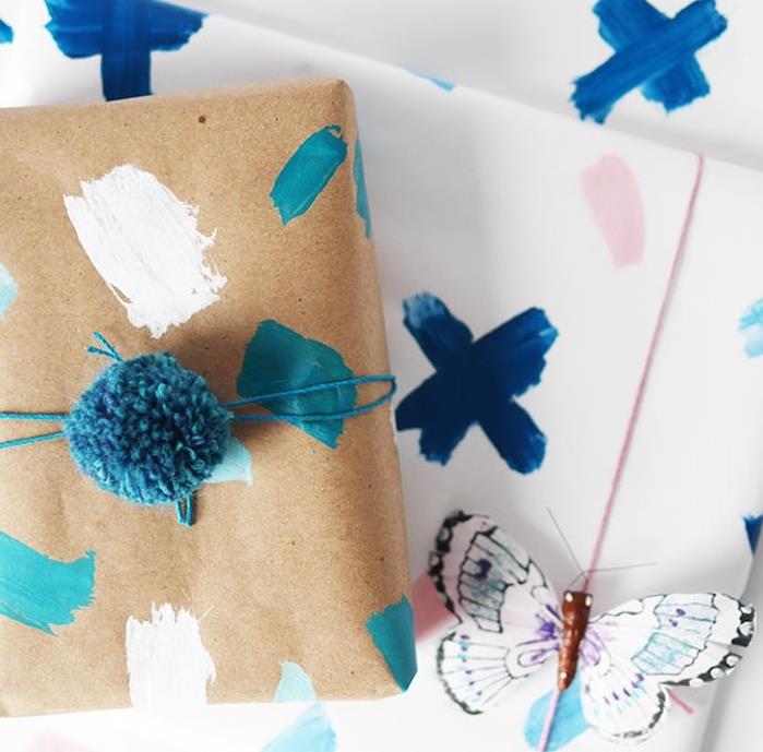 originalus dovanų pakavimo modelis, baltas popierius ir kraftpopierius su dažais, mėlyna pompa ir dekoratyviniu drugeliu