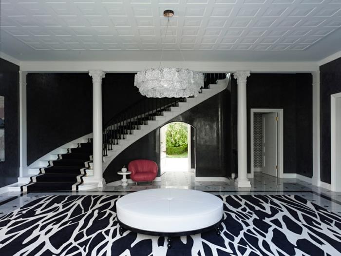 baltas apvalus stalas, juodos ir baltos grindys, madingi spiraliniai laiptai, didelė balta lubų lempa