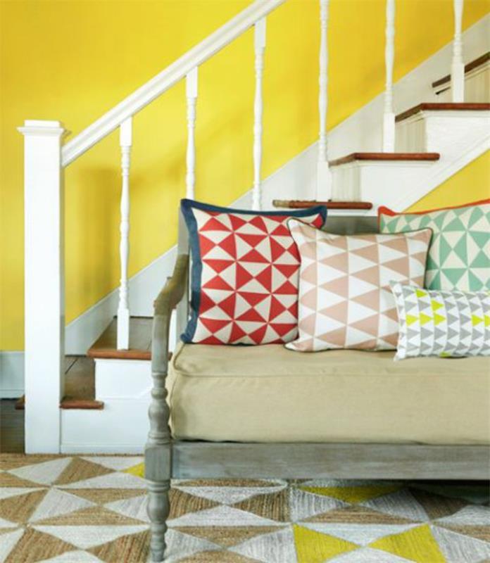 mediniai ir balti laiptai, geltonai dažytos sienos, grafinės dekoratyvinės pagalvėlės, grafinis kilimas