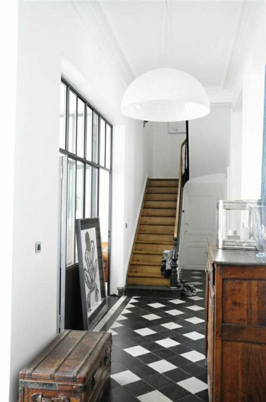leseno-stopnišče-bela-črna-ploščice-beli-stenski-lestenec-bela-temno-leseno pohištvo