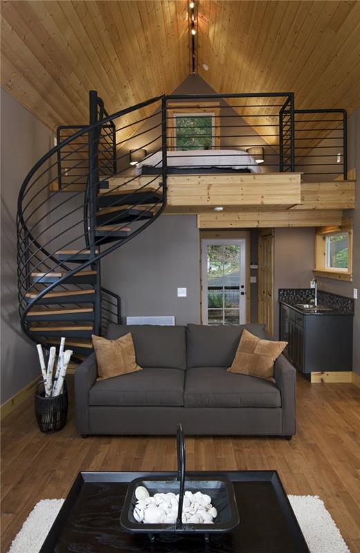 spiraliniai laiptai, mansardinis miegamasis, pilka sofa, praktiška virtuvė ir svetainė