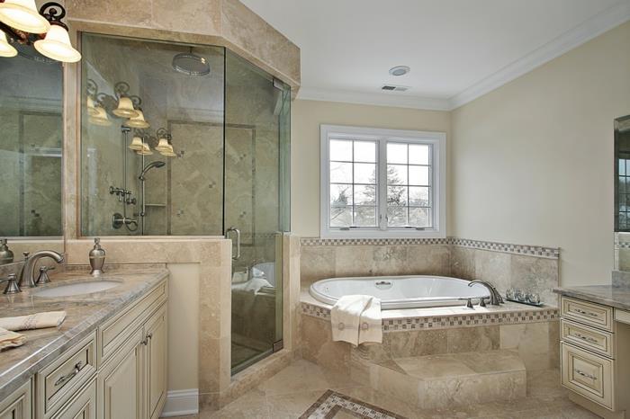 mozaikinės grindys, graži, senovinė lubų lempa, kreminės spalvos spintelės, travertino vonios kambarys