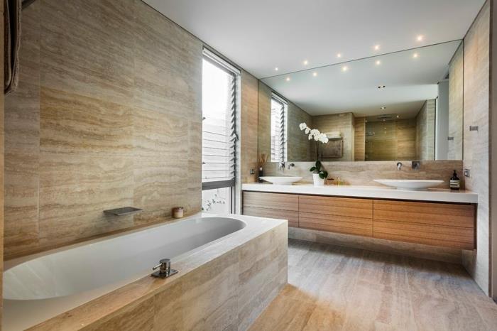 natūralaus akmens vonios kambarys, didelis stačiakampis veidrodis, praustuvė su dviguba kriaukle, travertino grindys ir siena