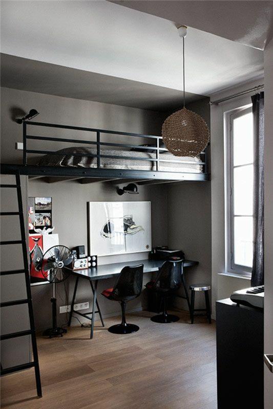 taupe parketas, baltos lubos, lova su juodo metalo turėklais, juodos kopėčios, uždėtos virš stalo, studento miegamojo dekoras, dvi juodos kėdės, rutulinė šviesa smėlio spalvos audinio siūlais
