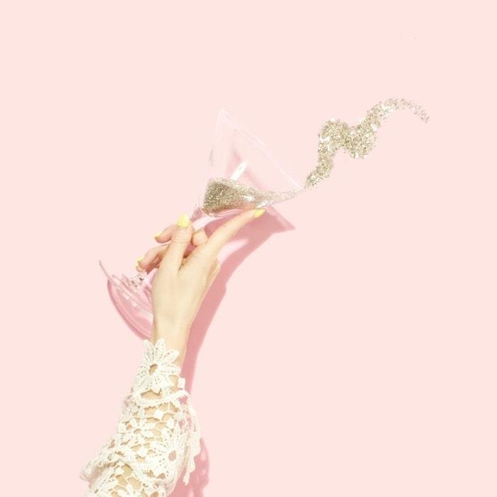 pastel estetik, işlemeli saplı bir el ve pipetlerle dolu bir bardak şampanya