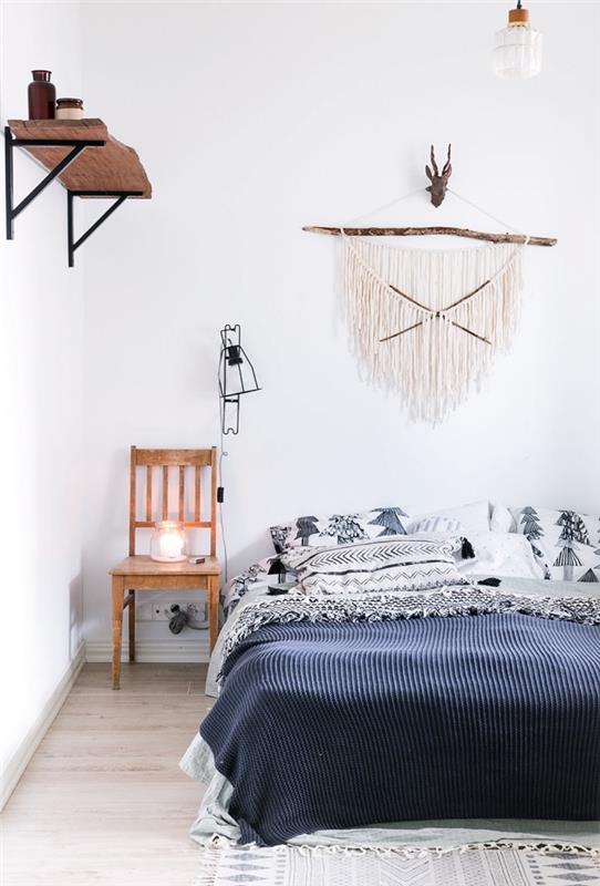prašmatnaus bohemiško miegamojo su baltomis sienomis su šviesiomis medinėmis grindimis ir medžio masyvo sienine lentyna pavyzdys, lovos modelis, padengtas pagalvėlėmis ir boho prašmatnus pledas
