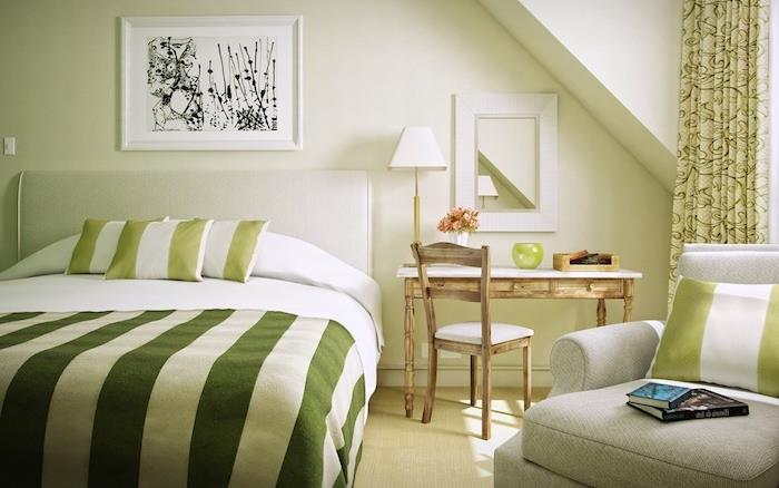 inci grisi kanepe ve kirli beyaz yatak başlığı, yeşil ve beyaz nevresimler, retro şık ahşap masa ve sandalye ile yeşil yatak odası dekorasyon fikri