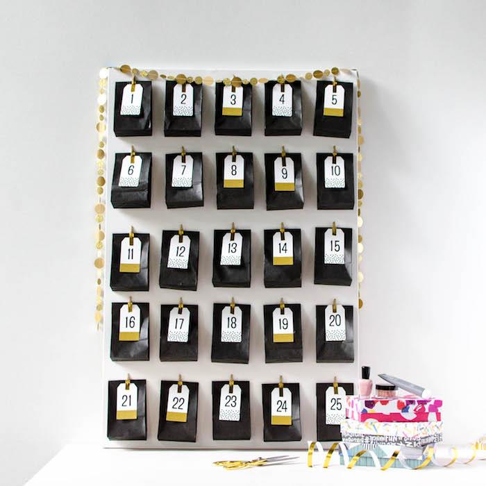 originalus grožio advento kalendorius juoduose maišeliuose su sunumeruotomis dovanų etiketėmis, įklijuotomis ant baltos ant sienos pakabintos plokštės