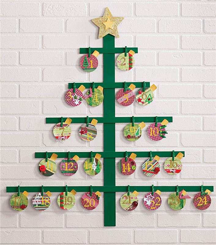 Advento kalendoriaus kūrimas iš medinių lentų, perdažytų žaliai, spalvingų kalėdinių rutuliukų, kabančių ant drabužių segtukų ant plytų sienos