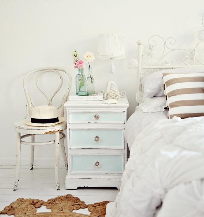nuskustas prašmatnus miegamojo modelis, balta ir mėlyna naktinė spintelė, baldai patina, dėvėta kėdė, baltos, pilkos ir rudos spalvos patalynė, baltas parketas