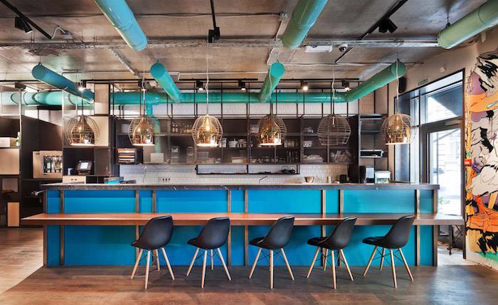 mavi orta ada, siyah İskandinav sandalyeler, orijinal sarkıt lambalar, ahşap zemin, siyah metal raflar, açık mavi borular ile endüstriyel şık mutfak düzeni