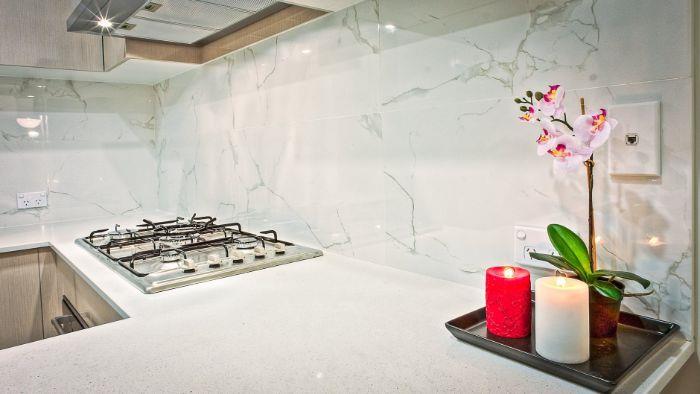 primer balzamske marmorne kuhinje v kuhinji z belo delovno ploščo in fasado iz svetlega lesa