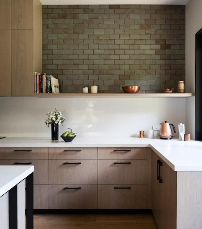 virtuvės modelis su žema medine spintele ir baltu stalviršiu, medine lentyna ir žalia plytų siena, įdomiais dekoratyviniais priedais
