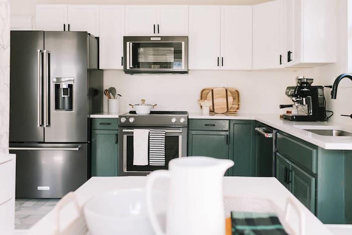 sumontuotas virtuvės modelis su alyvuogių žalia pagrindo spintele ir baltu stalviršiu, baltos spintelės, prietaisai, šaldytuvas, mikrobangų krosnelė, nerūdijančio plieno orkaitė