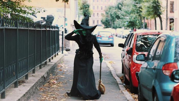 oz cadısı yüz ve vücut boyama solucanı, geleneksel uzun siyah cadı elbisesi, süpürge ve cadı şapkası