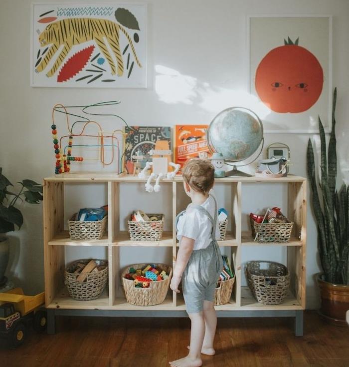 žemos medienos spintelė su žaislų laikymo krepšeliais, dekoratyviniais gyvūnų ir augalų sienų plakatais, vaikų žaislais