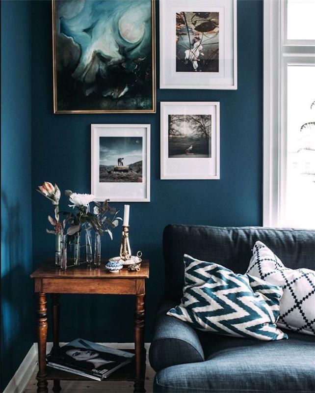 ideja o petrolejski modri barvi v starodobni dnevni sobi, stena s slikarskimi okvirji, lesena stranska miza, sivo modra zofa, dekoracija soliflores