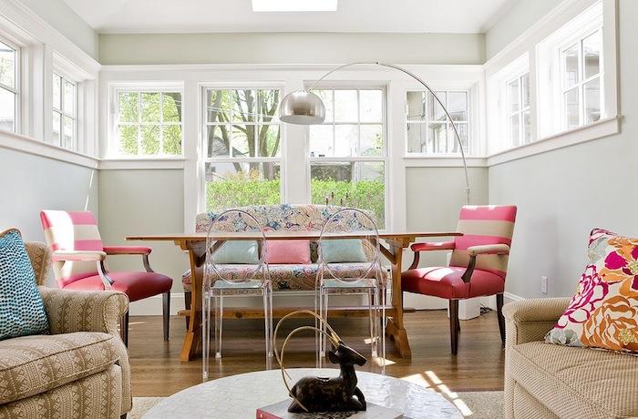 inci grisi boyalı duvar, ahşap masa, pembe ve bej sandalye, şoklanmış eski püskü çiçekli kanepe ve bej kahverengi kanepe ve koltuk örneği