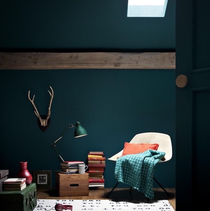 bencinsko modri model notranjosti, skandinavski stol, kup knjig, smaragdno zelena škatla, bela preproga s črnimi črkami, izpostavljen žarek, deko jelenjad
